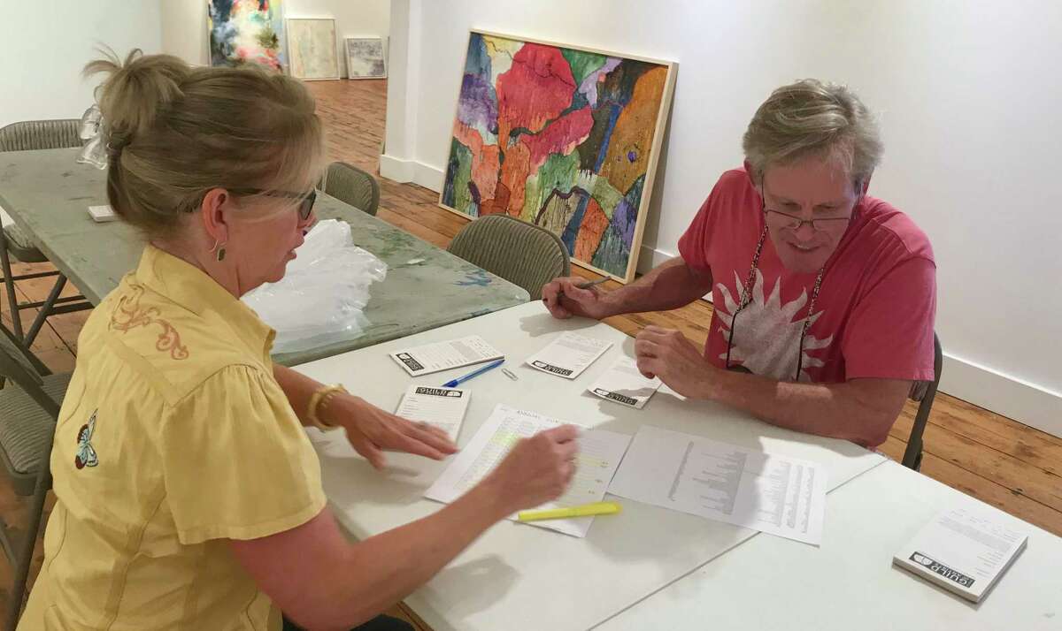 Guild board member, Tina Sturges, takes in artwork for the Annual Juried Show from artist, Michael Brennecke.
