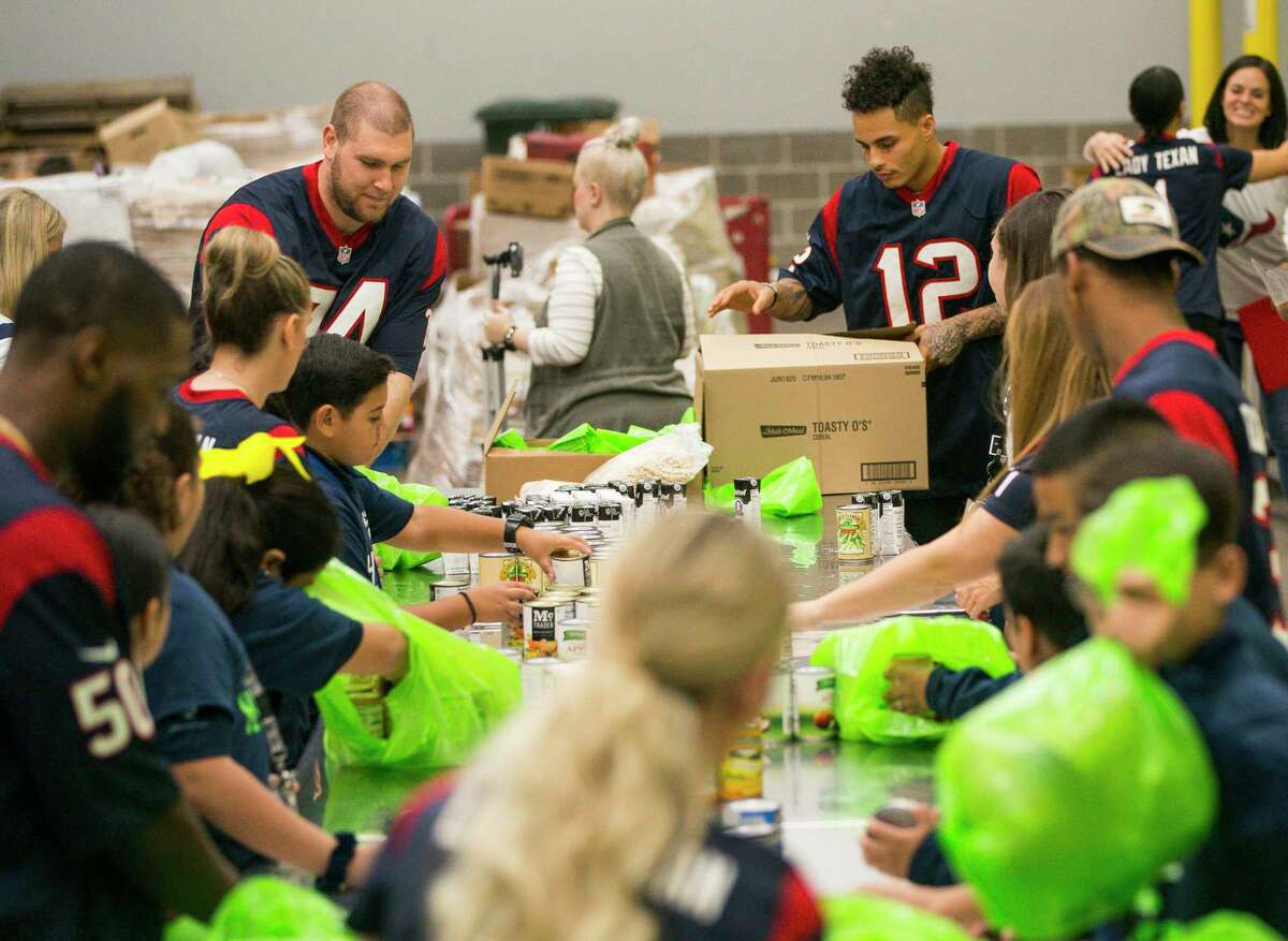 Houston Texans tackle Max Scharping and wide receiver Kenny Stills pack bags of food with students from YES Prep East End and other members of the Texans organization during a kickoff event for Huddle Against Hunger, a partnership between the Houston Texans and the Houston Food Bank, at the food bank's main facility in east Houston, Tuesday, Sept. 17, 2019. Huddle Against Hunger is a curriculum designed to teach school students about hunger and poverty.