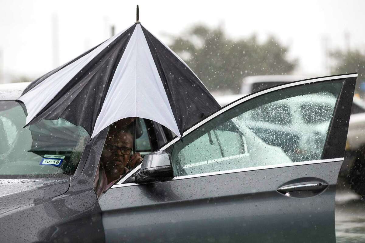 A woman closes her umbrella after getting into her car during a rain storm stemming from rain bands spawned by Tropical Storm Imelda near I-45 and Almeda-Genoa on Tuesday, Sept. 17, 2019, in Houston.