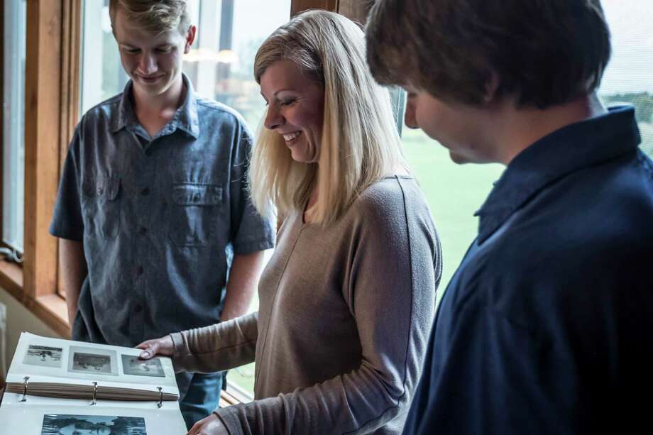 Julie Worthen and her two sons — Garrison Worthen, 13, right; and Jonathan Worthen, 16 — look through an old photo album featuring images of her family dating back to the 1800s. Photo: Nina Robinson