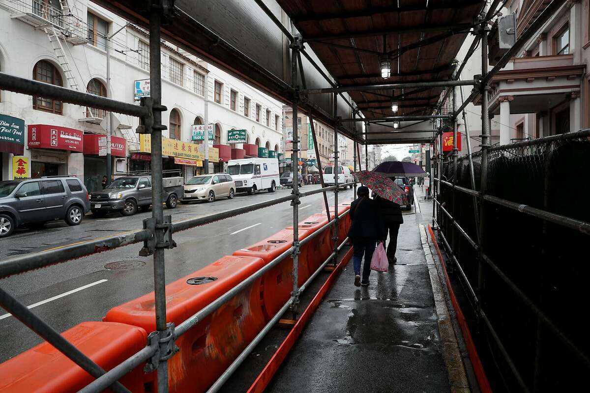 People traverse the pedestrian walkway around the Central Subway project which runs under Chinatown where a train station is under construction at the corner of Stockton and Washington streets, in San Francisco, Calif. on Fri. January 5, 2018.