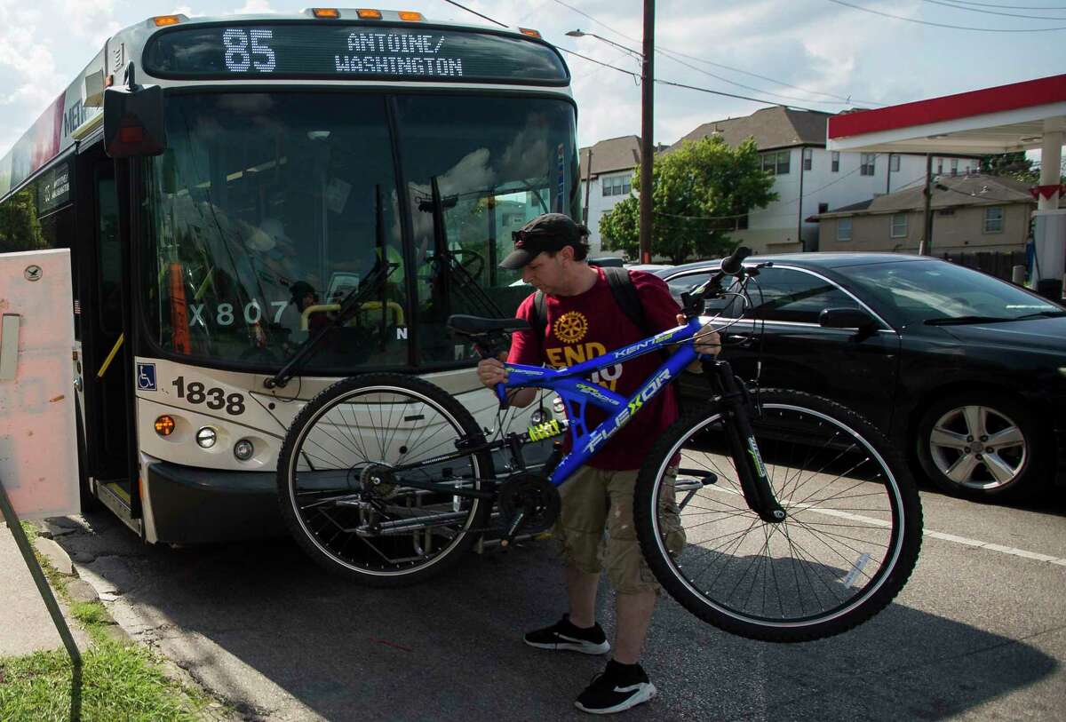 A rider removes his bicycle from the front of a Metropolitan Transit Authority Route 85 bus at the intersection of Washington and Studemont in Houston on June 10, 2019.