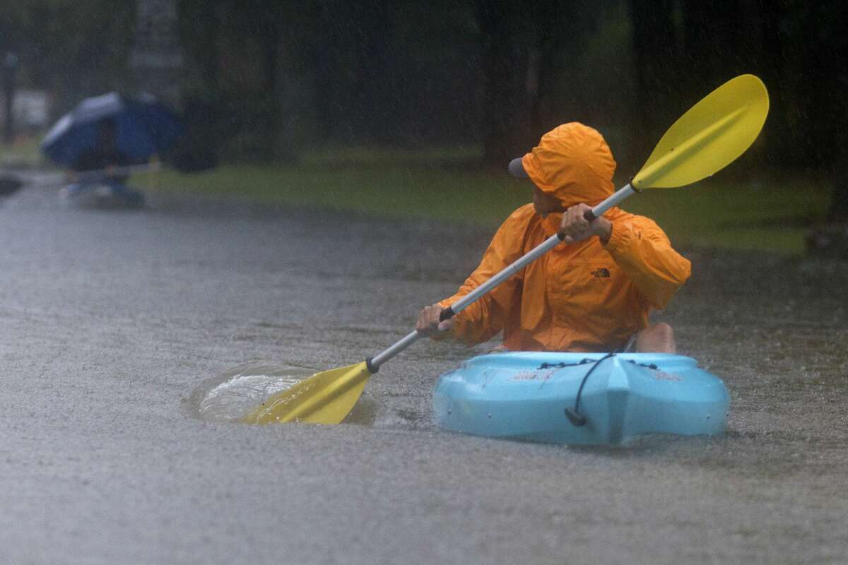 A man uses a kayak to navigate Kings Manor Drive as rain from Tropical Depression Imelda inundate the area, Thursday, Sept. 19, 2019, in Kingwood.