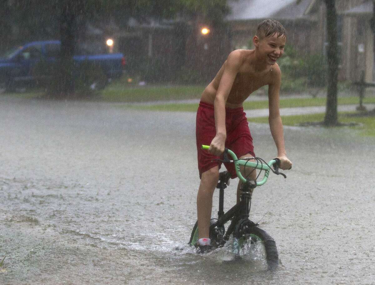 A kid rides his bike near Kings Manor Drive as rain from Tropical Depression Imelda inundate the area, Thursday, Sept. 19, 2019, in Kingwood.