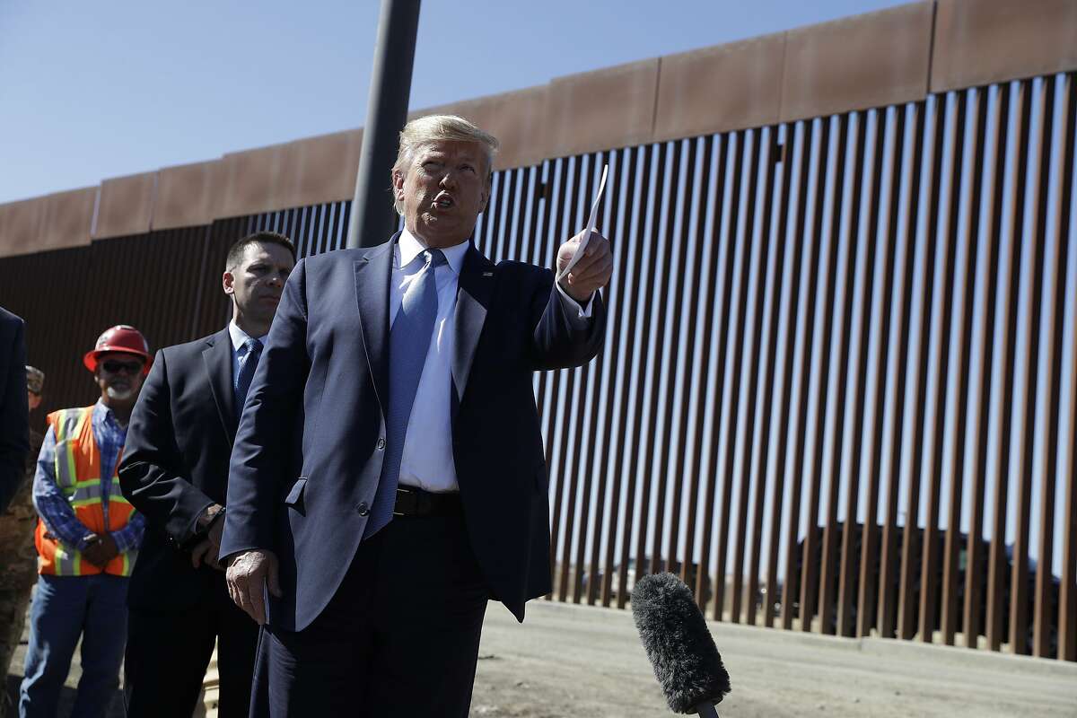 President Donald Trump talks with reporters as he tours a section of the southern border wall, Wednesday, Sept. 18, 2019, in Otay Mesa, Calif., as acting Homeland Secretary Kevin McAleenan listens, second from left. (AP Photo/Evan Vucci)
