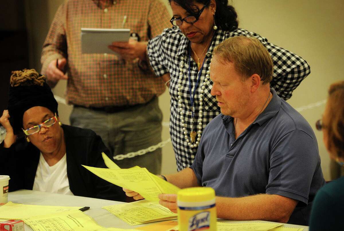 Absentee ballot head moderator Tom Errichetti, right, and deputy moderator Rosalina Roman-Christy, center, look over absentee ballots during a recount of results from last week's primary at the Margaret Morton Government Center in Bridgeport, Conn. on Wednesday, September 23, 2015.