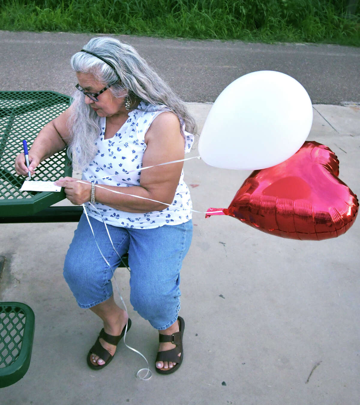 Family and friends of Claudine Luera gathered at North Central Park on Saturday for a remembrance vigil to mark the first anniversary of her death. White and heart-shaped red balloons with messages attached were released in her honor.