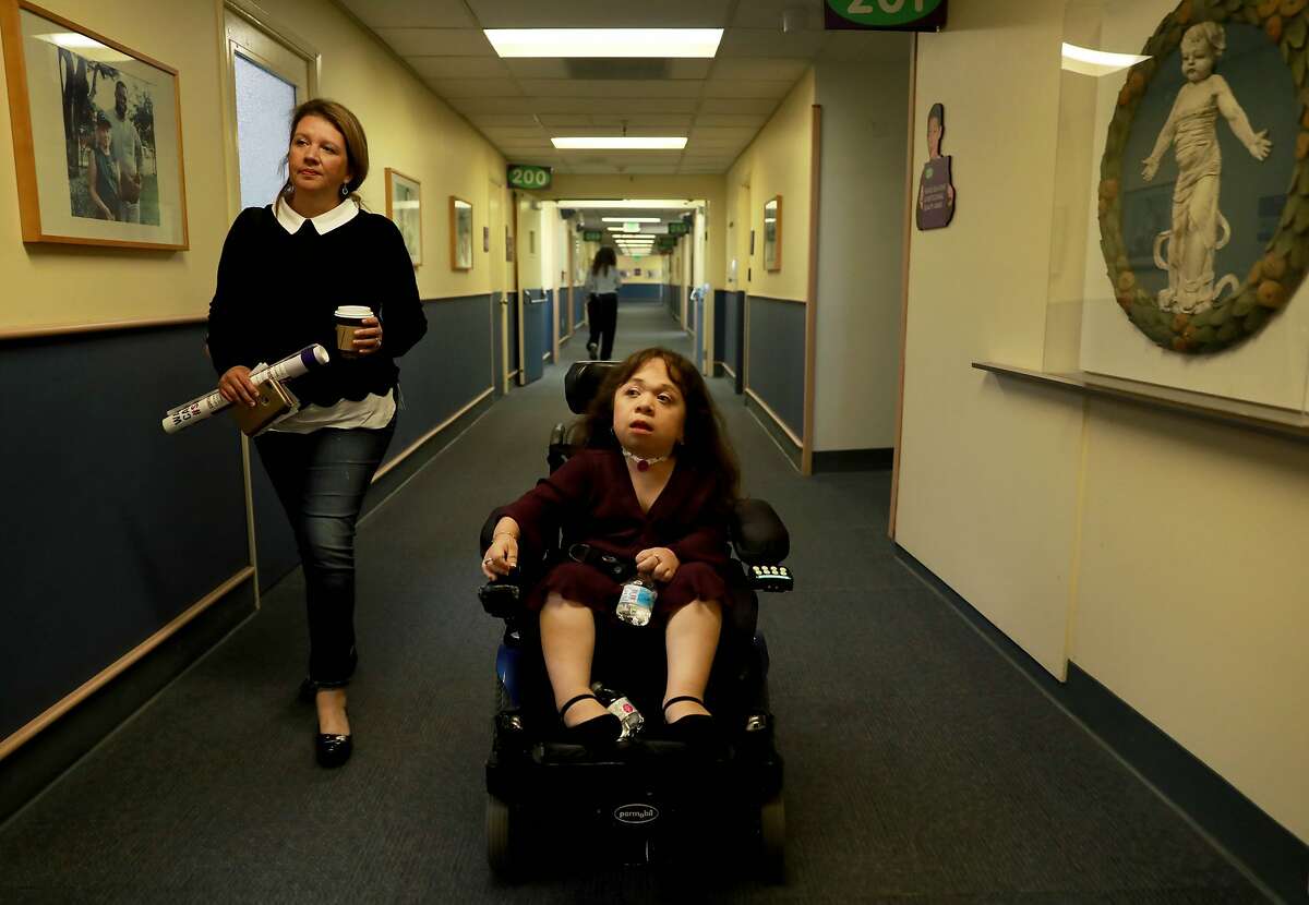 Karla Bueso, left, walks to the cafeteria with her daughter Isabel at UCSF Benioff Children's Hospital Oakland in Oakland, Calif., on Friday, September 6, 2019. Isabel is a severely disabled Guatemalan woman slated for deportation this month. However, she may have a chance to stay in the United States, where she has lived for the past 16 years. The government has agreed to reopen immigration cases for Bueso and other beneficiaries of deferred action, a legal program that provides deportation relief to individuals who are critically ill. The administration ended the program earlier this year. Staff at UCSF Benioff in Oakland, where Bueso receives critical weekly treatment for an extremely rare genetic condition known as Maroteaux-Lamy Syndrome, will rally on her behalf as she prepares to testify before a Congressional committee next week.
