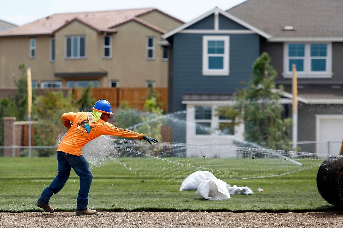 Andres Flores pulls netting as he helps lay sod at a playground in Tracy Hills on Thursday, September 5, 2019 in Tracy, CA.