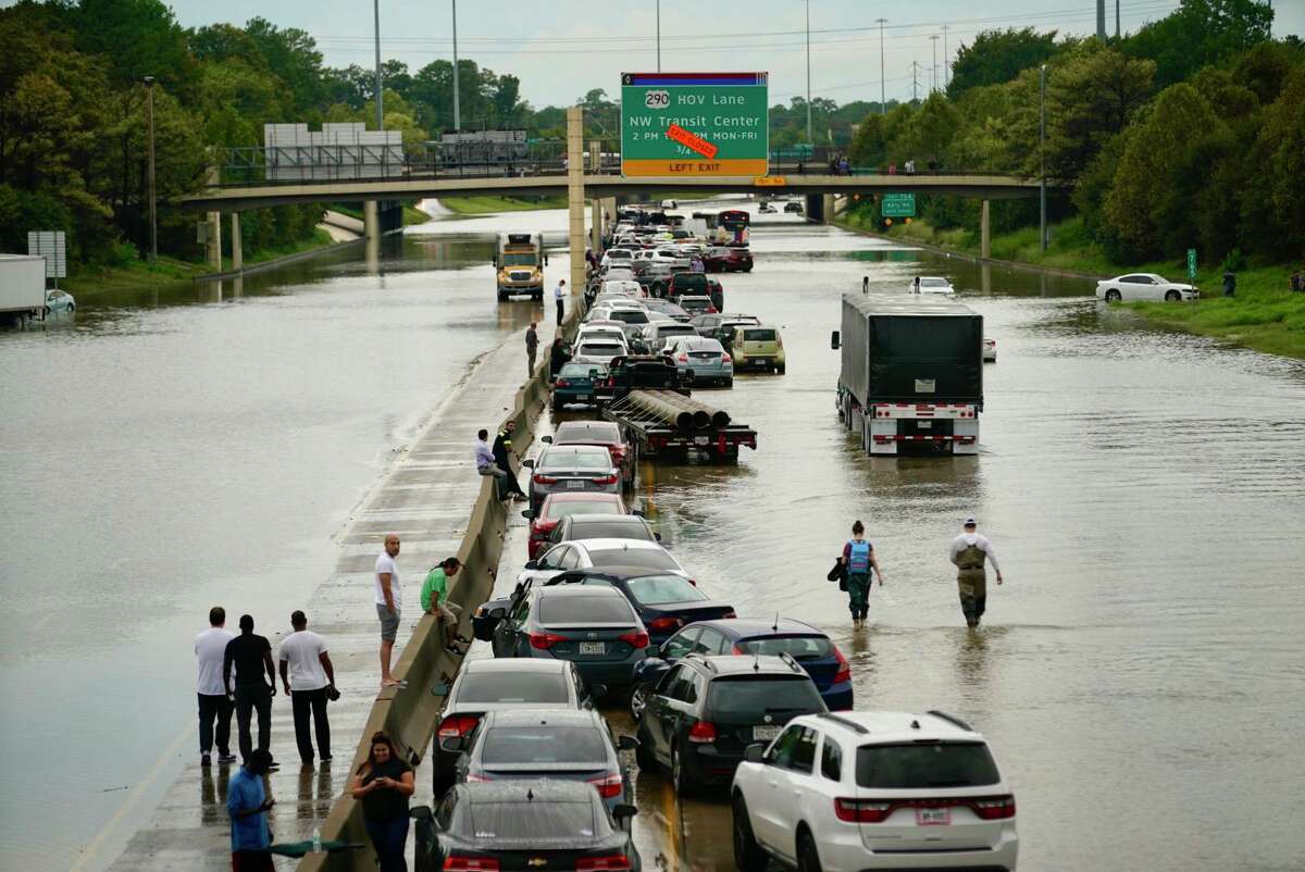 People wait outside of their stranded vehicles along Interstate 10 westbound at T.C Jester on Sept. 19, 2019. Tropical Depression Imelda's sudden cruel swing-back stunned thousands across the region who thought the worst was over. It was not.