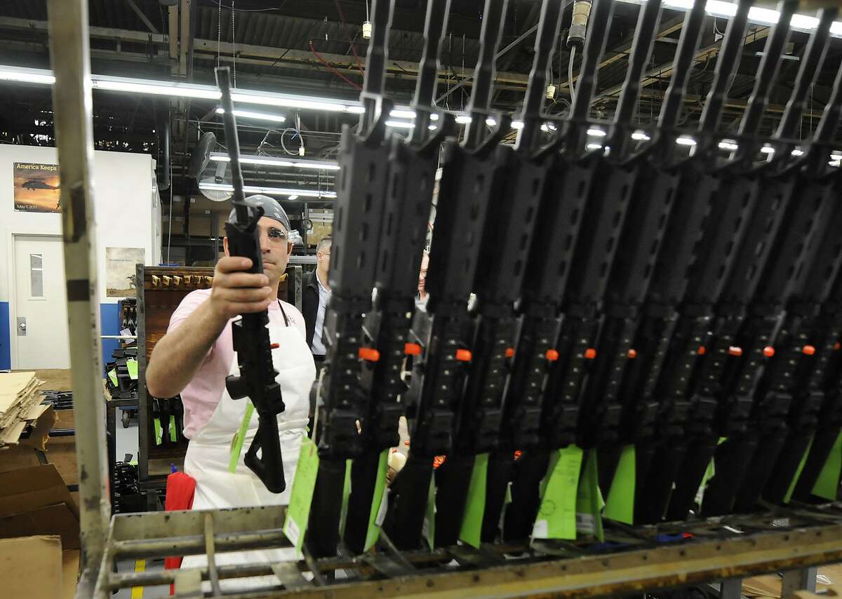 Sergio Pereira adds a completed Colt rifle to a rack of newly assembled guns at the company headquarters in West Hartford in this 2013 file photo. The company said Thursday it was suspending production of AR-15 rifles for the civilian market. (Michael McAndrews/Hartford Courant/TNS)