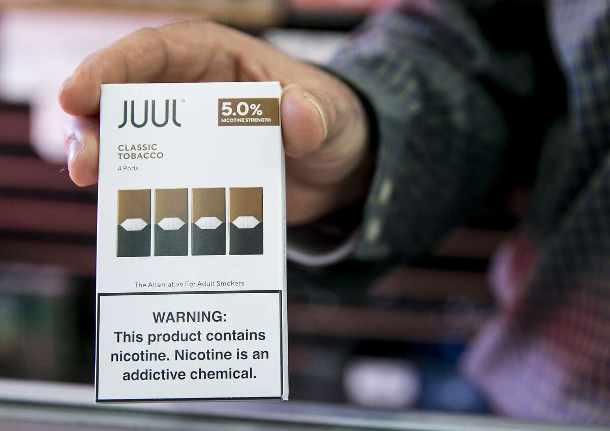 Walid Rahman holds a Juul cartridge container while working behind the counter at The Town Smoke Shop in the Mission district of San Francisco, Calif. Thursday, March 21, 2019.