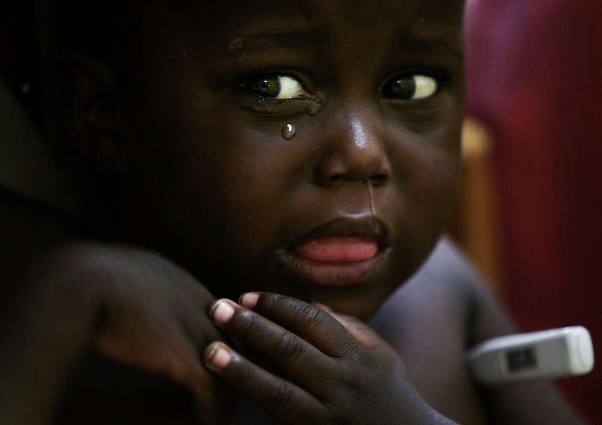 2005 | KAMPALA, UGANDA — A child cries while having his temperature taken as he is examined at the Paediatric Infectious Diseases Clinic (PIDC) of Mulago Hospital in Kampala, Uganda, on May 13, 2005. The clinic was one of only a few HIV treatment facilities for pediatrics in Uganda, where it is estimated that there are approximately 100,000 HIV infected children. On this day, a Friday, the clinic saw 187 patients. Triage is the entry point for medical visits, and is also where growth and development is monitored and vital signs are taken and documented at each monthly medical visit. Temperature is an important vital sign at the PIDC in Uganda as high temperature can be a sign of either an HIV-related infection or of malaria.