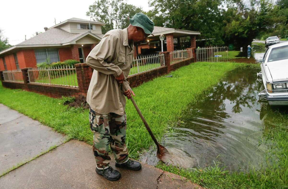 Arness Rochon tries to clear the ditch in front of his home in Independence Heights neighborhood after Imelda swept through Houston.