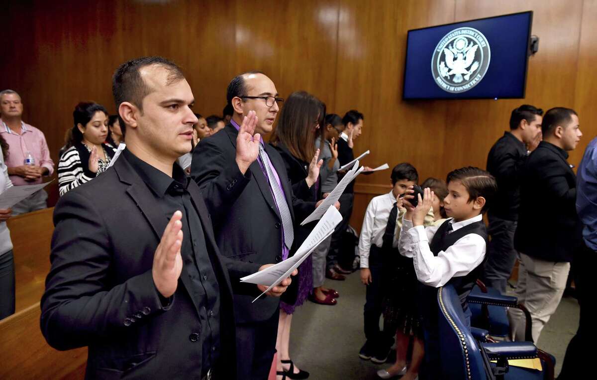 Bashir Safi, left, recites the Oath of Allegiance during a naturalization ceremony at U.S. District Court in Bridgeport on Sept. 18, 2019, 10 years after coming to this country as a refugee from Afghanistan.