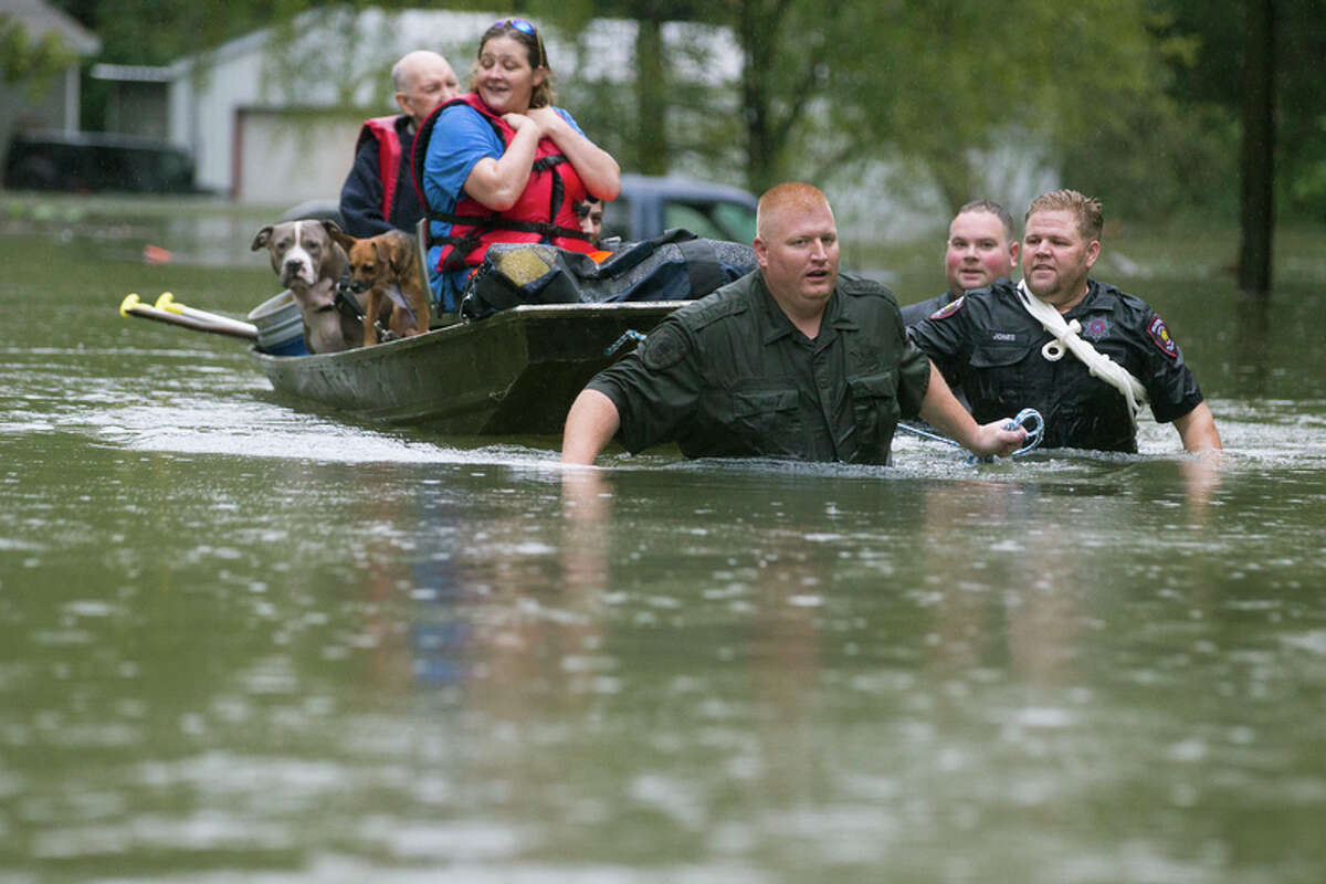 Splendora Police Lt. Troy Teller, left, Cpl. Jacob Rutherford and Mike Jones pull a boat carrying Anita McFadden and Fred Stewart from their flooded neighborhood inundated by rains from Tropical Depression Imelda on Thursday, Sept. 19, 2019, in Spendora.