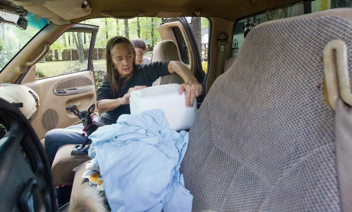 Margret Cameron unpacks a container of medicine in her fiancé’s truck she, him and his daughter have stayed in for the last two days after leaving their home, Friday, Sept. 20, 2019, in Splendora. Water from nearby Caney Creek sent five and a half feet of water from Tropical Depression Imelda into their home.