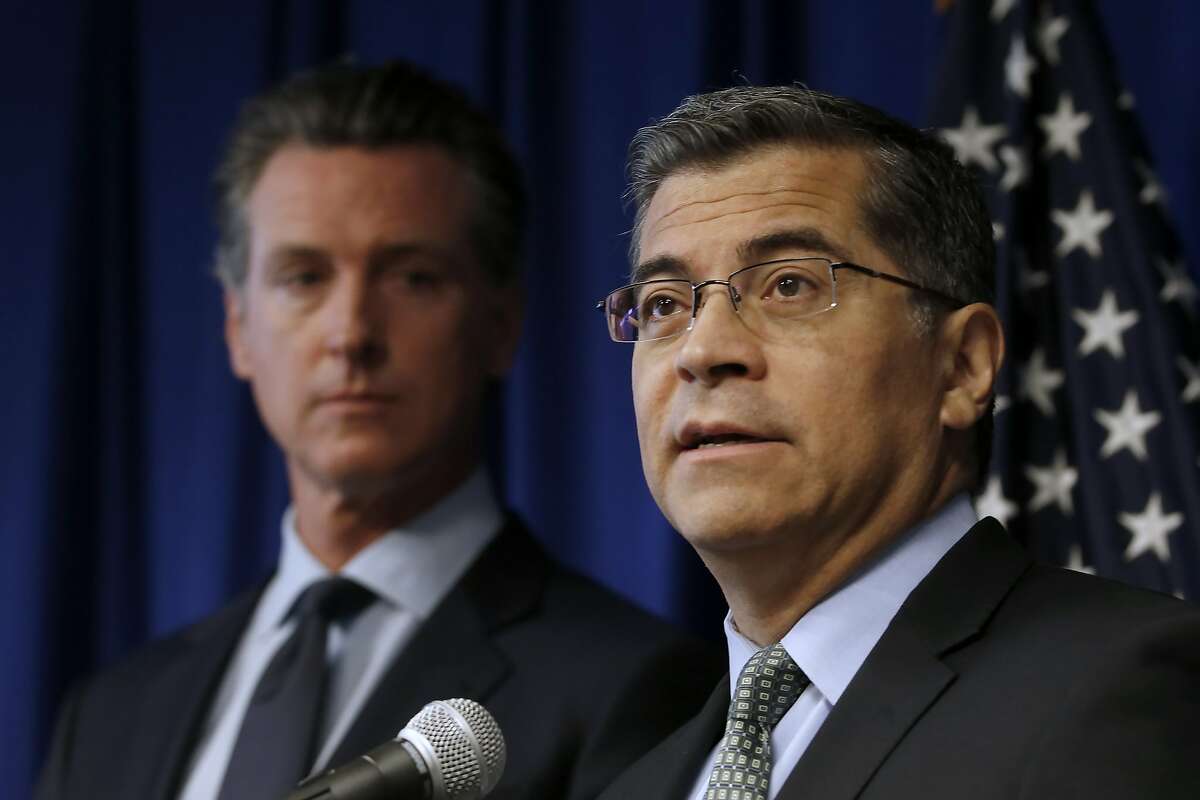 FILE - In this Sept. 18, 2019 file photo California Attorney General Xavier Becerra, right, flanked by Gov. Gavin Newsom, discusses the Trump administration's pledge to revoke California's authority to set vehicle emissions standards that are different than the federal standards, during a news conference in Sacramento, Calif. Twenty-three states have sued to stop the Trump administration from revoking California's authority to set emission standards for cars and trucks. Becerra is leading the lawsuit filed Friday, Sept. 20 along with Newsom and the California Air Resources Board. (AP Photo/Rich Pedroncelli,File)