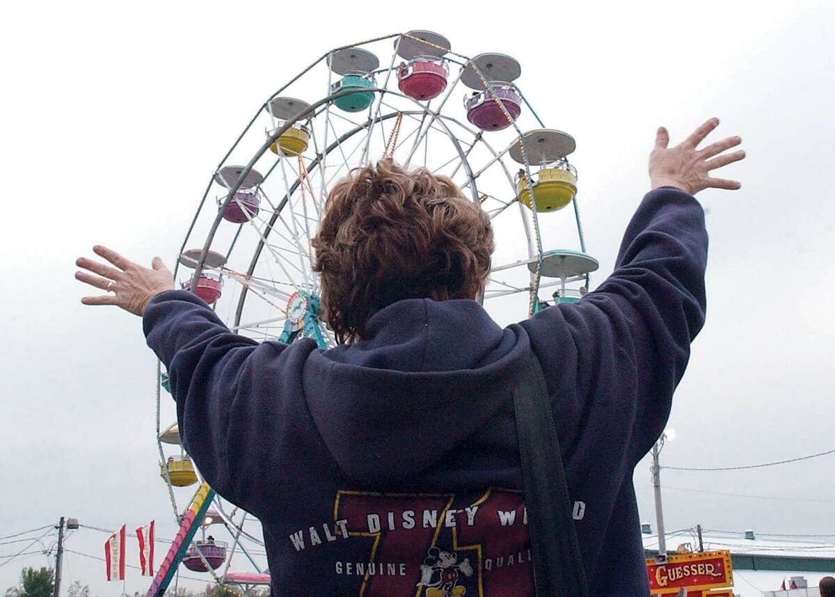 Jane Solomine of East Haven waves to her husband and children riding on the Ferris wheel at the Durham Fair in this September 2003 archive shot.