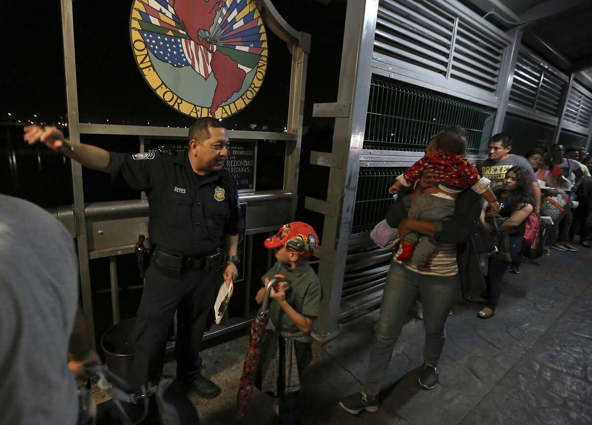A U.S. Customs and Border Protection officer gives instructions to migrants who are on their way to apply for asylum in the United States, on International Bridge 1 as they depart Nuevo Laredo, Mexico, early Tuesday, Sept. 17, 2019. Tent courtrooms opened Monday in two Texas border cities to help process thousands of migrants who are being forced by the Trump administration to wait in Mexico while their requests for asylum wind through clogged immigration courts. (AP Photo/Fernando Llano)