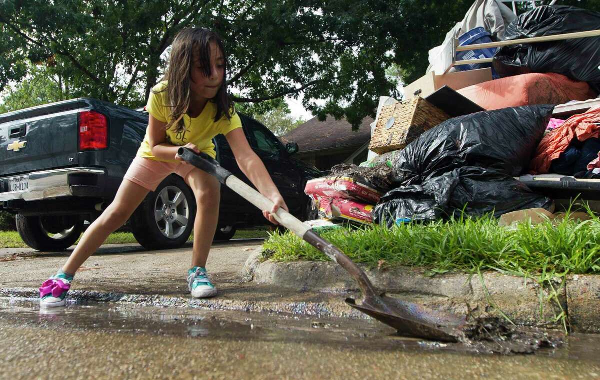 Angeleen Garza helps move floodwater and debris infront of their home in the Elm Grove subdivision toward a nearby storm drain, Friday, Sept. 20, 2019, in Kingwood.