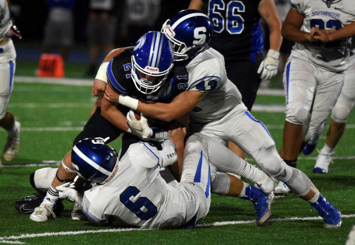 Darien’s Will Kirby (21) battles for extra yards against Southington’s Jack McManus (6) and Max Casella (43) during a football game in Darien on Friday.