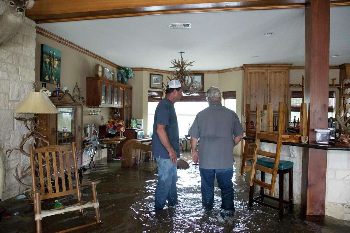 Cousins Richie Devillier, 56, left, and Steve Devillier, 59, look around Steve's flooded house on Devillier Road on Friday, Sept. 20, 2019, in Winnie. While water has started to go down on the south side of the Interstate Highway 10, the north side of the highway was still under deep water.