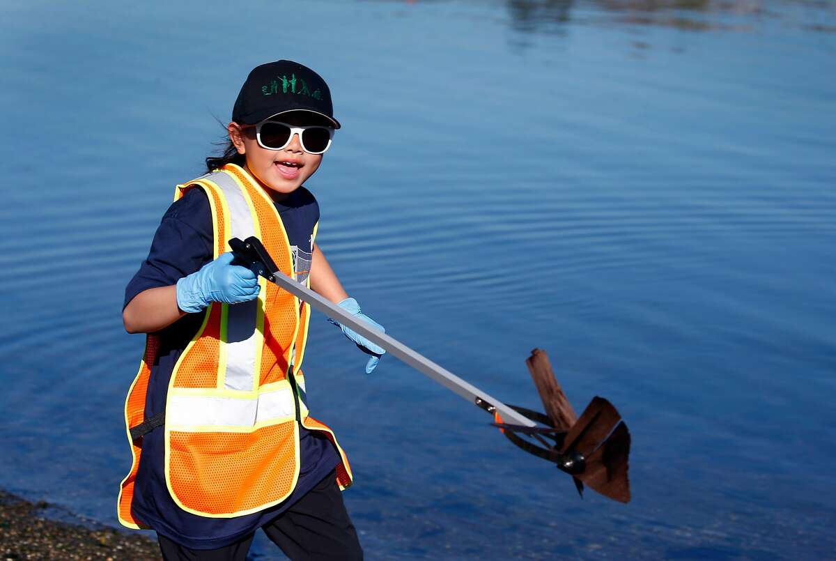 Emily Lin, 9, carries trash retrieved from Islais Creek to a garbage bag in San Francisco, Calif. on Saturday, Sept. 21, 2019. More than 3,500 volunteers pre-registered to participate in the city for the Battle For The Bay 2019 competition on Coastal Cleanup Day pitting San Francisco against Oakland and San Jose.