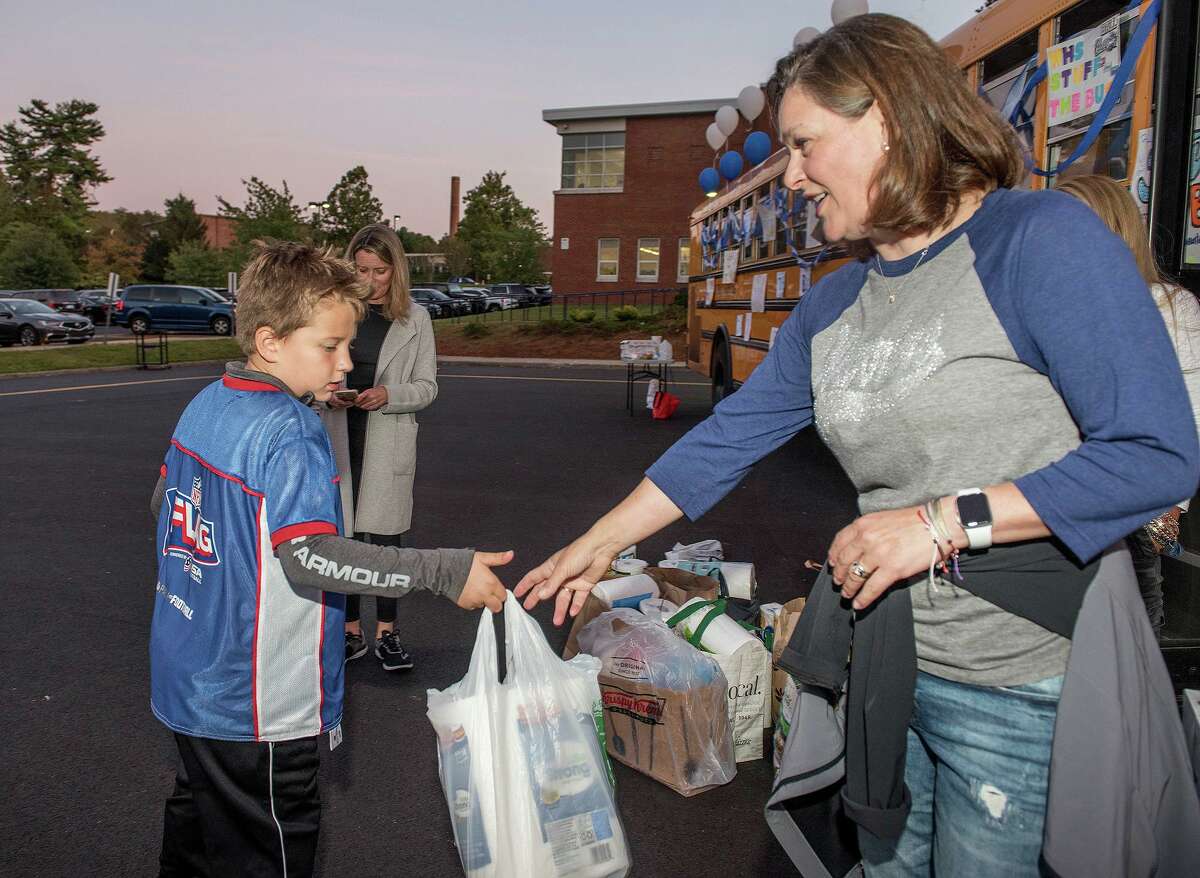 Henry Dempster, 7, hands a bag containing items for Wilton's food pantry to Jennifer Angerame at the Stuff the Bus event on Sept. 20.