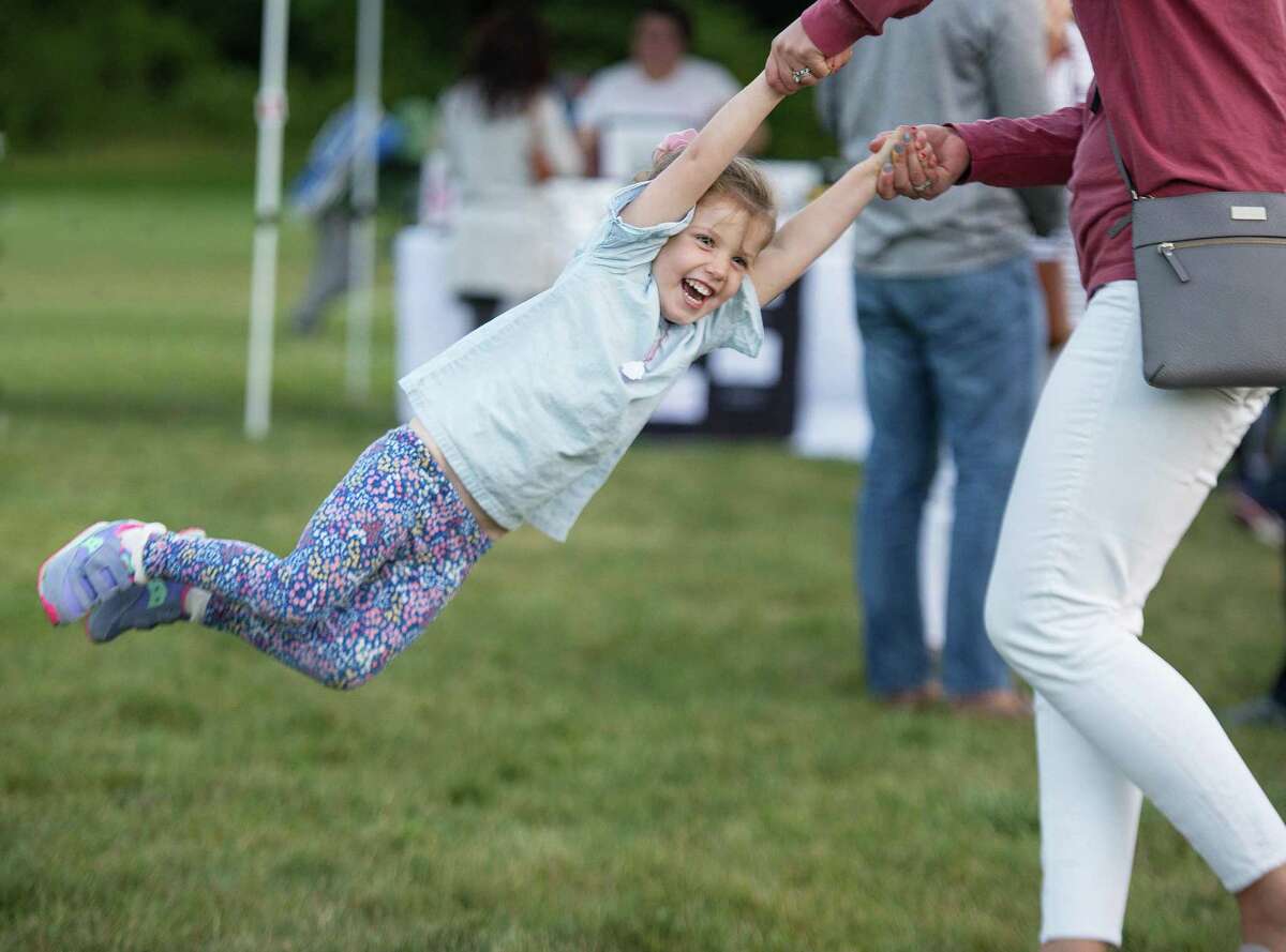 Avery Noonan, 3, of Ridgefield swings with her mom at RidgeFest, a launch party for the e-commerce website RidgefieldMarketplace.com, on Friday, Sept. 13.