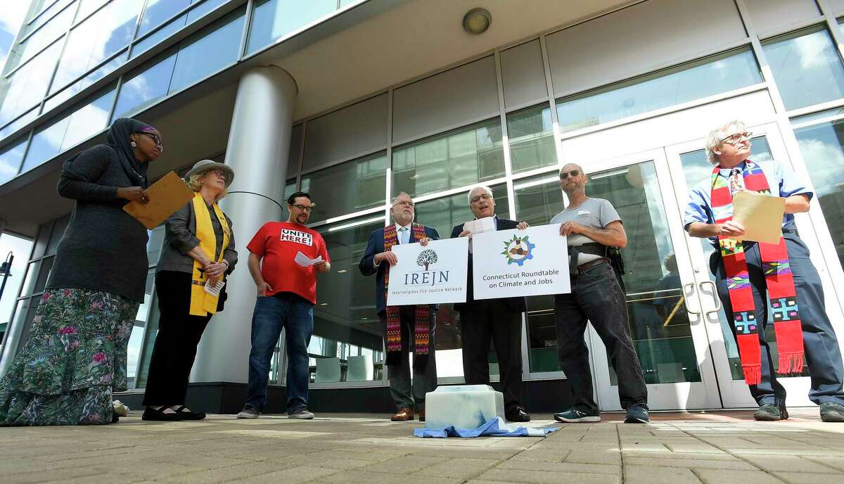 With an burial urn containing ashes from Stamford-based Castleton Commodities International’s coal-fired power plant in Bow, N.H., activists call for the plant’s shutdown, during a gathering in front of Castleton Commodities offices in Stamford, Conn., on Sept. 24, 2019.