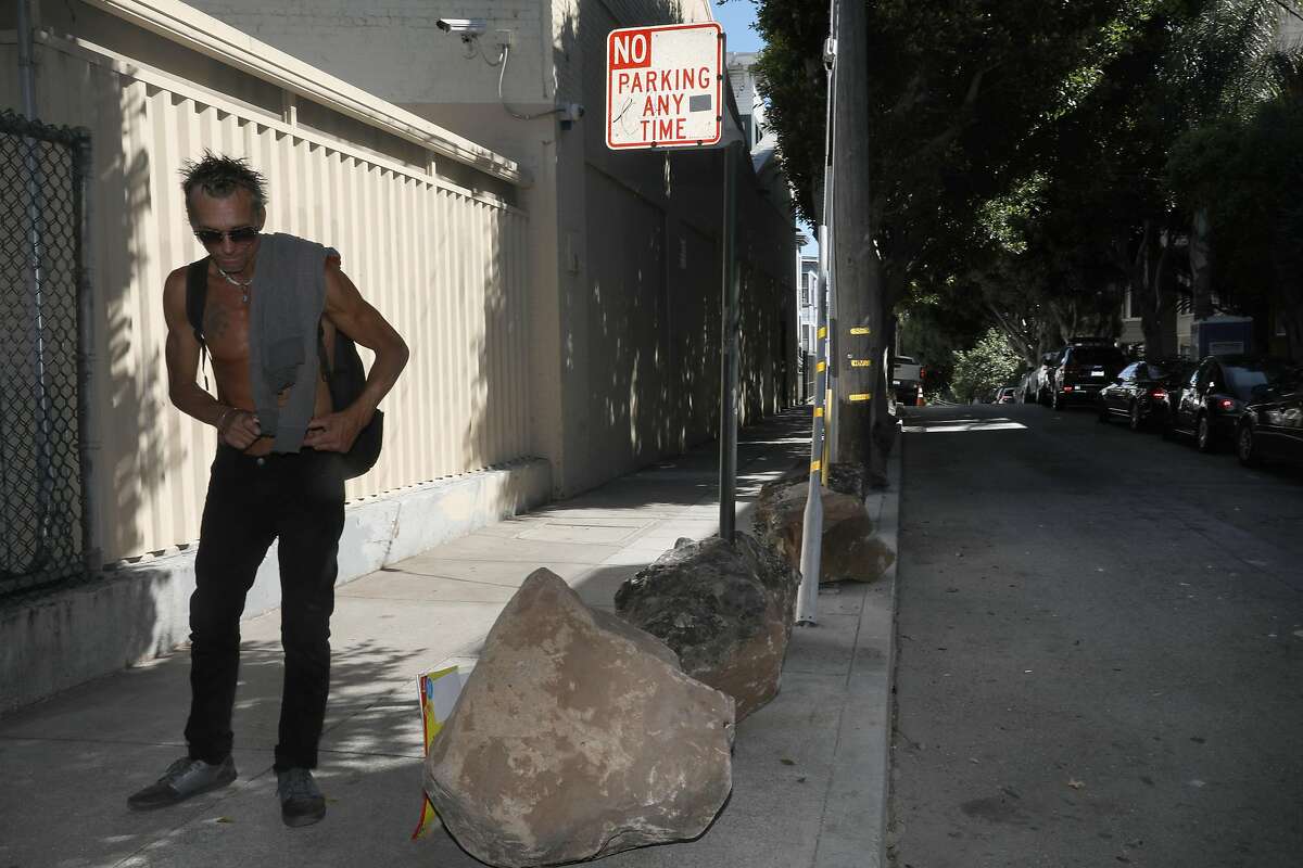 Eric Mills gets up after taking a rest on a boulder at Clinton Park just off of Dolores St. on Tuesday, September 24, 2019, in San Francisco, Calif. Someone has put boulders on the sidewalk to keep the homeless tents out and the Department of Public works has no plans to remove them.
