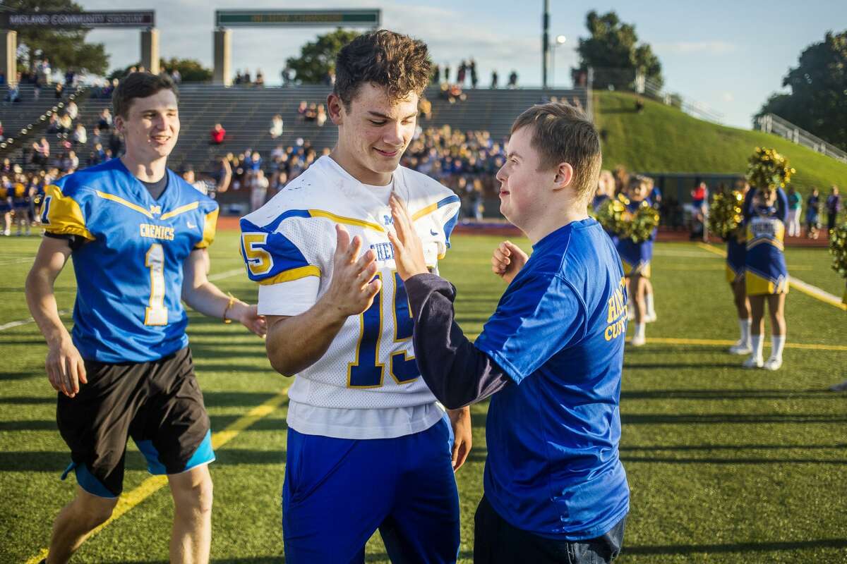 Midland High student Jared Walter, right, high-fives varsity football player Hunter Nagel, left, during Victory Day, an event which gave students with special needs an opportunity to score a touchdown with the Chemics' football team or cheer with the cheer team, Monday, Sept. 23, 2019 at Midland Community Stadium. (Katy Kildee/kkildee@mdn.net)