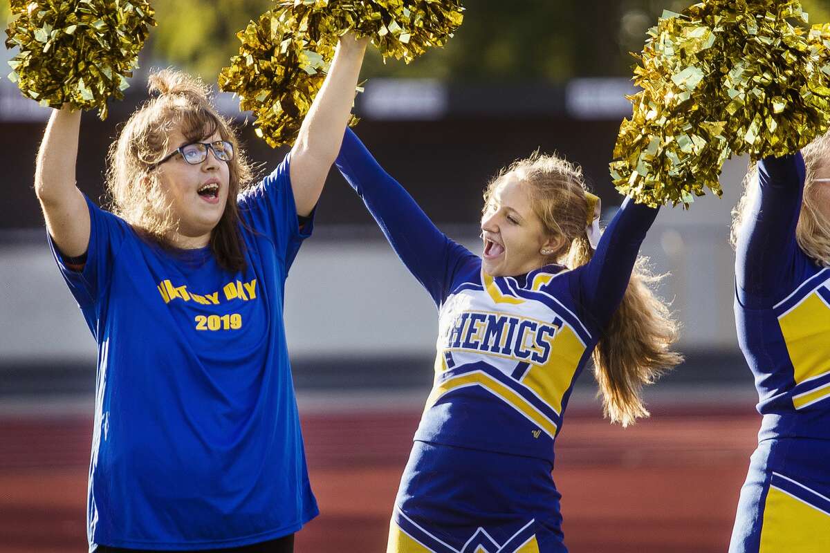 Midland High senior Amber Andrick, left, cheers alongside sophomore and varsity cheerleader Caelie Cervantes, center, during Victory Day, an event which gave students with special needs an opportunity to score a touchdown with the Chemics' football team or cheer with the cheer team, Monday, Sept. 23, 2019 at Midland Community Stadium. (Katy Kildee/kkildee@mdn.net)