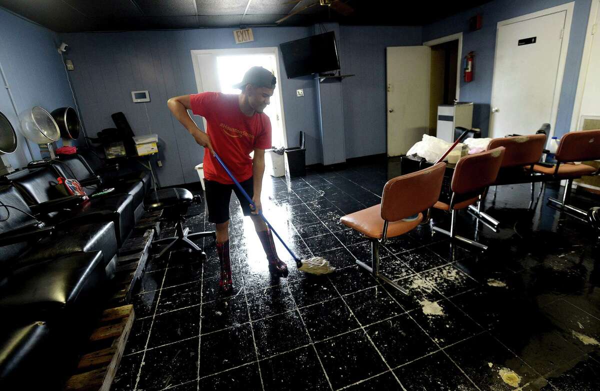 Coreyy Vee sweeps the flooded floor of Cuts and Curls on S. 4th Street in Beaumont as the process of recovery from Imelda's torrential rains and flooding begins throughout the region Friday. Photo taken Friday, September 20, 2019 Kim Brent/The Enterprise