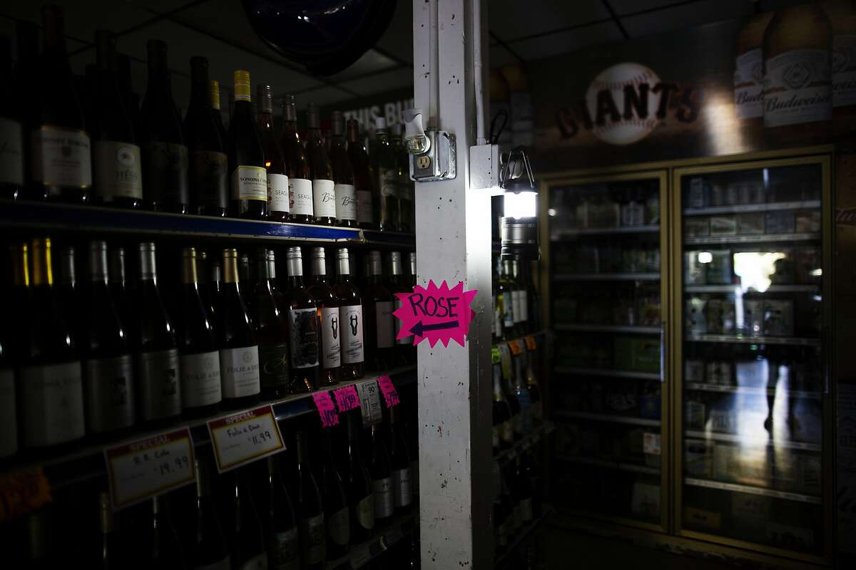 A lantern lights an isle of wine at the Calistoga Liquor, that had its electricity cut by PG&E in attempts to prevent fires during extreme fire conditions,Calistoga, September 25th, 2019. PG&E shut off electricity to parts of Calistoga in attempts to prevent fire started by their lines during extreme fire conditions. The first report of the Tubbs Fire came from Hwy 128 and Tubbs lane -where Calistoga Liquor store is located.
