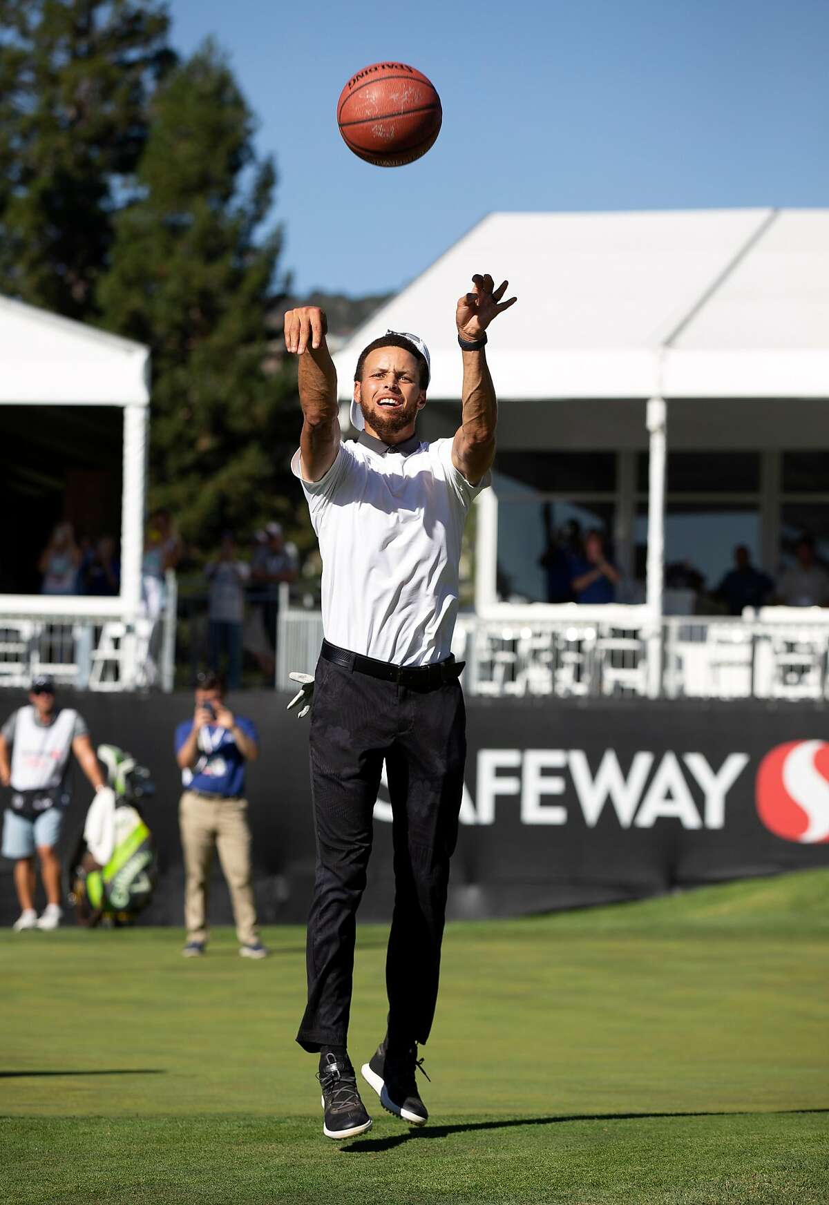 Golden State Warriors star Stephen Curry imitates his famous "shot from the tunnel" with a basketball hoop at the 17th hole during the Safeway Open pro-am golf event on Wednesday, Sept. 25, 2019 in Napa, Calif.