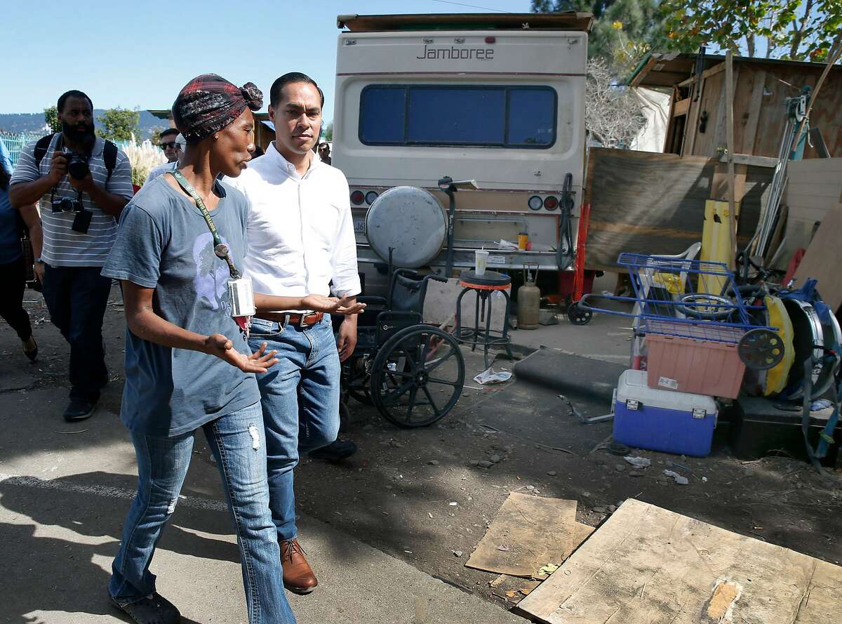 Markaya Spikes, a resident of a homeless encampment near the Home Depot off High Street for five years, leads former Secretary of Housing and Urban Development and Democratic presidential candidate Julian Castro on a tour of the camp in Oakland, Calif. on Wednesday, Sept. 25, 2019.