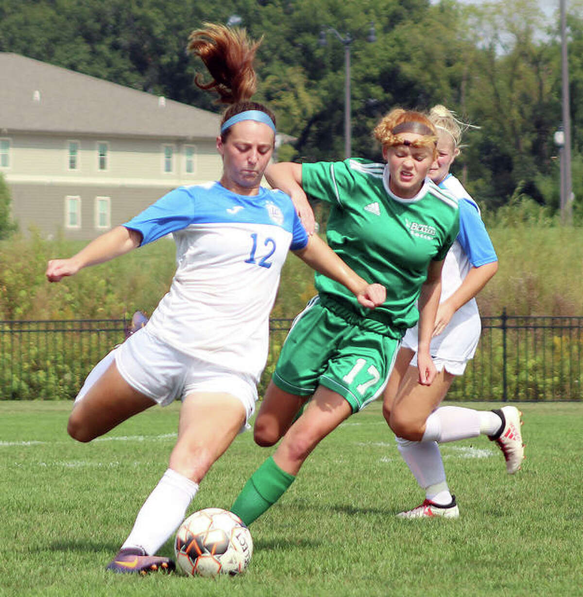 Cassie Hall of LCCC (12) looks to clear the ball away from John Wood College’s Abbie Reis Wednesday at Tim Rooney Stadium. LCCC won 11-0.
