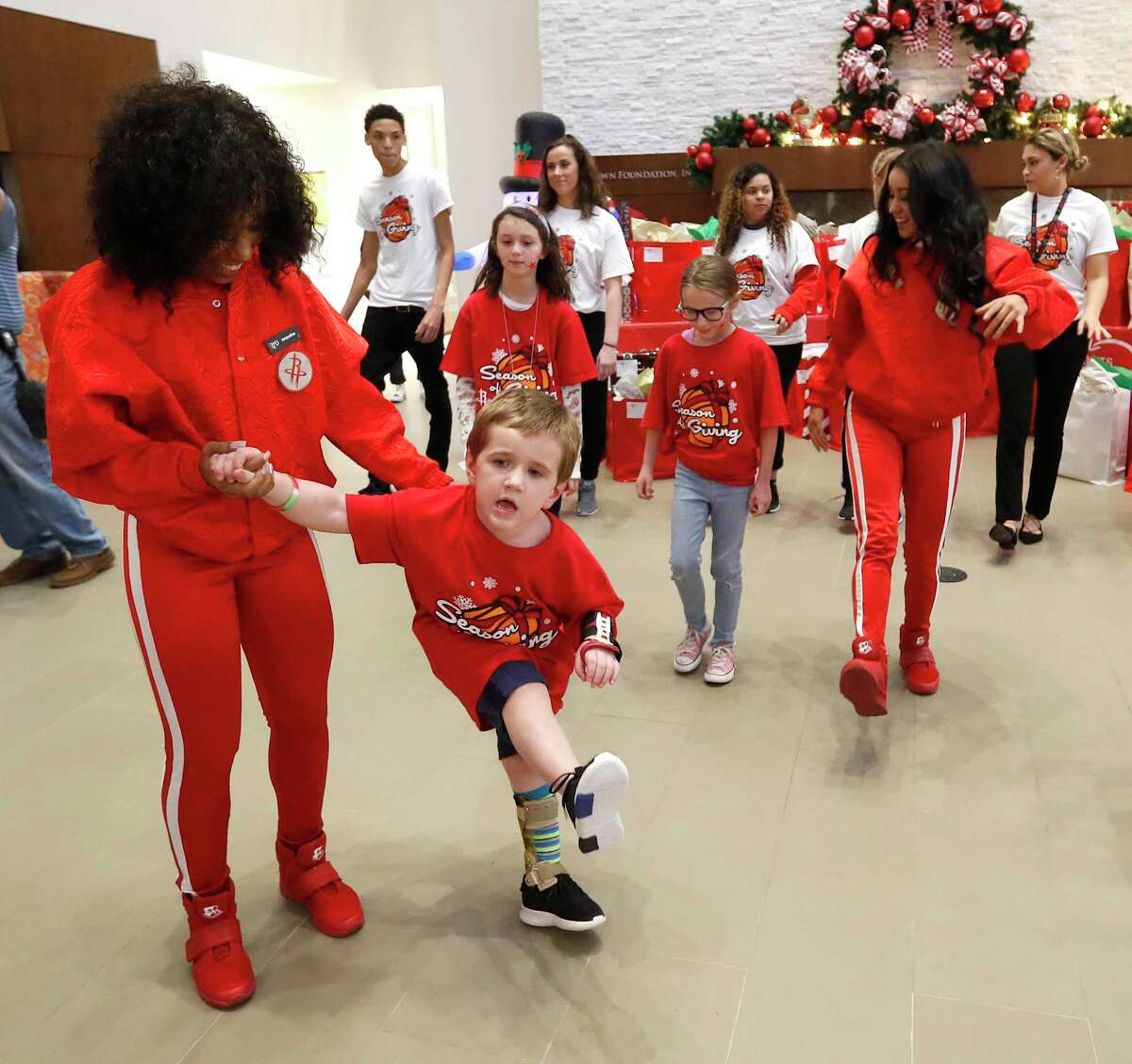 John Weekley, 4, dances with a Rockets Power Dancer before guard Eric Gordon and former player Carl Herrera hand out gifts to him and other children staying at the Ronald McDonald House. The Rockets and Southwest Airlines partnered to host a holiday party for seriously ill children being treated in the Texas Medical Center.