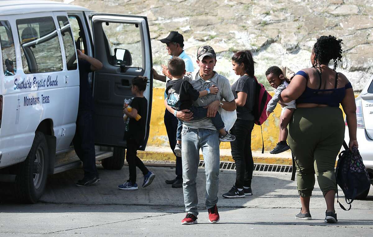 A migrant from Honduras carries his four year-old son in the parking lot of the Mexican Immigration office in Nuevo Laredo. Migrants from Central America and Cuba go to asylum hearings in Laredo, Texas, on Thursday, Sept. 19, 2019.