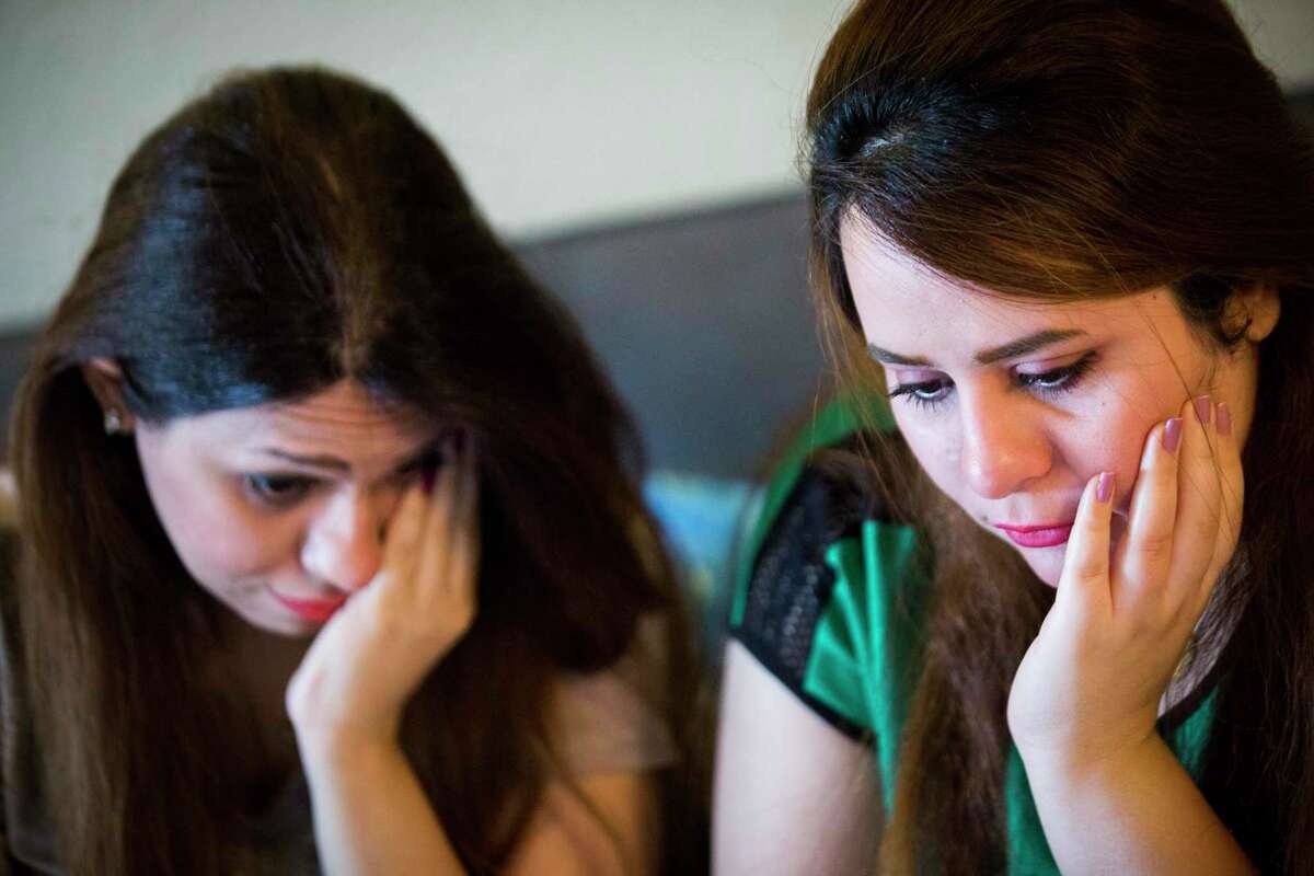 Sarah Ismaeil, left, 31, and her sister Dhuha Ameri, 26, hold back tears back while they speak with their parents in Iraq using a video chat application in August 2018 in Houston. The sisters had been waiting two years for their parents to join them in the United States. The Trump administration’s latest 2019 cuts mean many refugees who had been nearing the end of their vetting process likely will not be able to come this year.