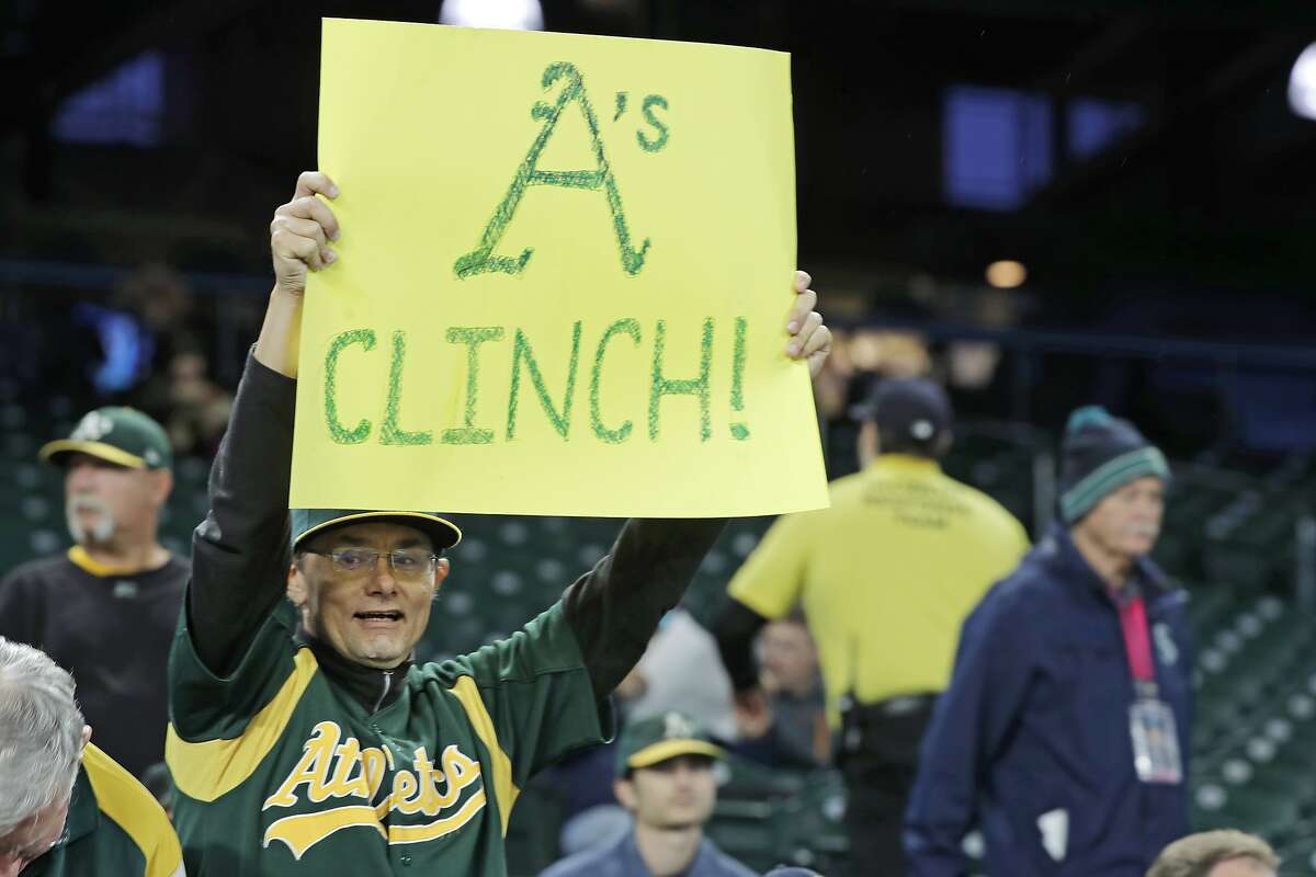 A fan holds a sign that reads "A's Clinch!" before a baseball game between the Seattle Mariners and the Oakland Athletics, Friday, Sept. 27, 2019, in Seattle.