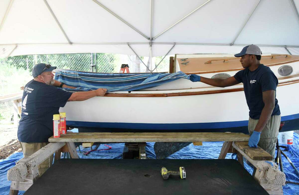 Program instructor Josh Mayo, left, and recent high school graduate Jeremiah Davis work to restore a boat at the SoundWaters Harbor Corps marine job training program at John J. Boccuzzi Park in Stamford, Conn. Thursday, Sept. 26, 2019. In partnership with DOMUS, recent Stamford Public Schools graduates learn valuable technical skills and connect with marine industry leaders to learn of career opportunities on the Stamford waterfront. This fall, members are restoring a catboat, and in the process learning fiberglass repair, carpentry, painting, varnishing, rigging, engine maintenance and more.