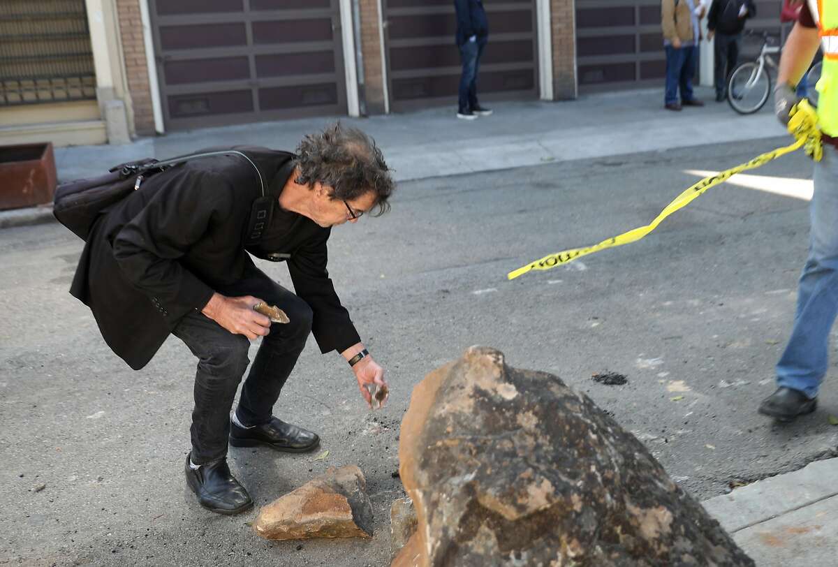 Richardd, a resident in the neighborhood, saves rock remnants from the boulders as public works removes them from the sidewalk along Clinton Park near Market at Dolores streets on Monday, Sept. 30, 2019, in San Francisco, Calif.