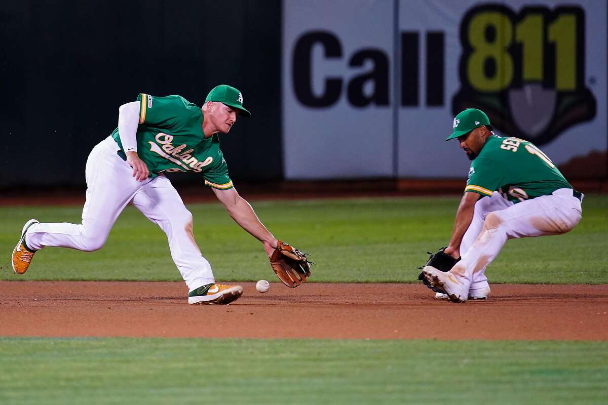 OAKLAND, CALIFORNIA - SEPTEMBER 20: Matt Chapman #26 of the Oakland Athletics fields a ball in front of Marcus Semien #10 during the seventh inning against the Texas Rangers at Ring Central Coliseum on September 20, 2019 in Oakland, California. (Photo by Daniel Shirey/Getty Images)