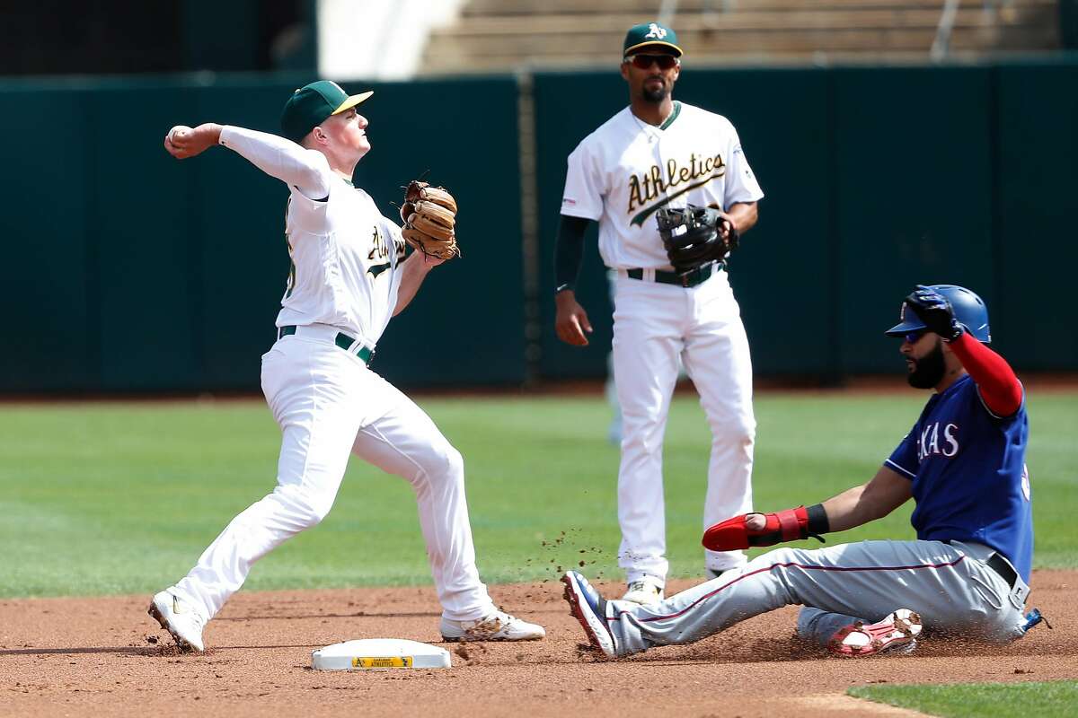 OAKLAND, CA - SEPTEMBER 22: Matt Chapman #26 of the Oakland Athletics turns a double play as Ronald Guzman #11 of the Texas Rangers slides onto second during the first inning at Ring Central Coliseum on September 22, 2019 in Oakland, California. (Photo by Stephen Lam/Getty Images)
