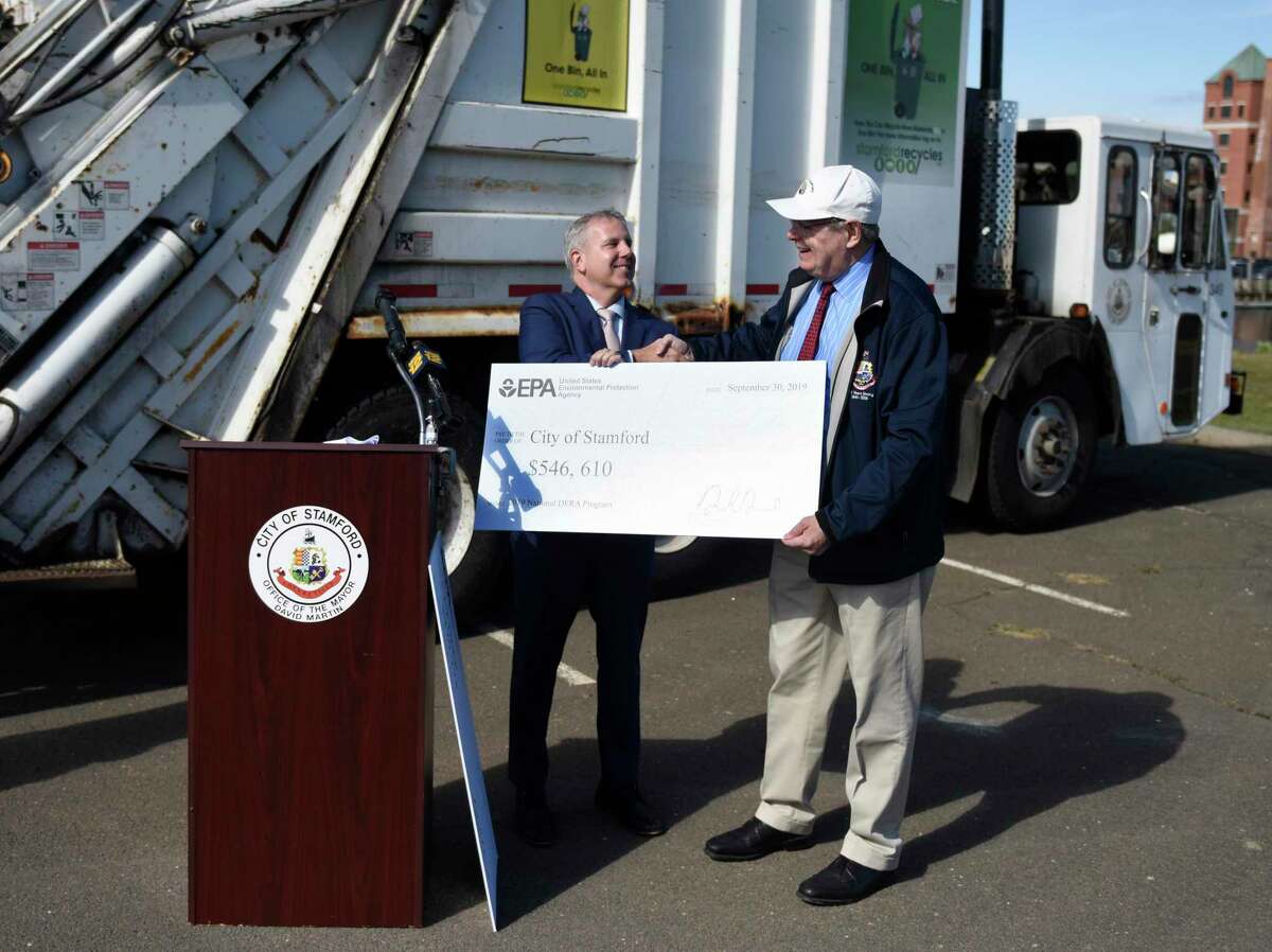 Stamford Mayor David Martin, right, recieves a check from EPA Regional Administrator Dennis Diesel to go toward the city's new garbage trucks at the Stamford Transfer Station in Stamford, Conn. Monday, Sept. 30, 2019. The city will soon replace seven diesel-engine garbage trucks with new trucks that meet 2019 EPA emissions standards, costing around $2 million minus a $546,610 reimbursement from the Environmental Protection Agency.