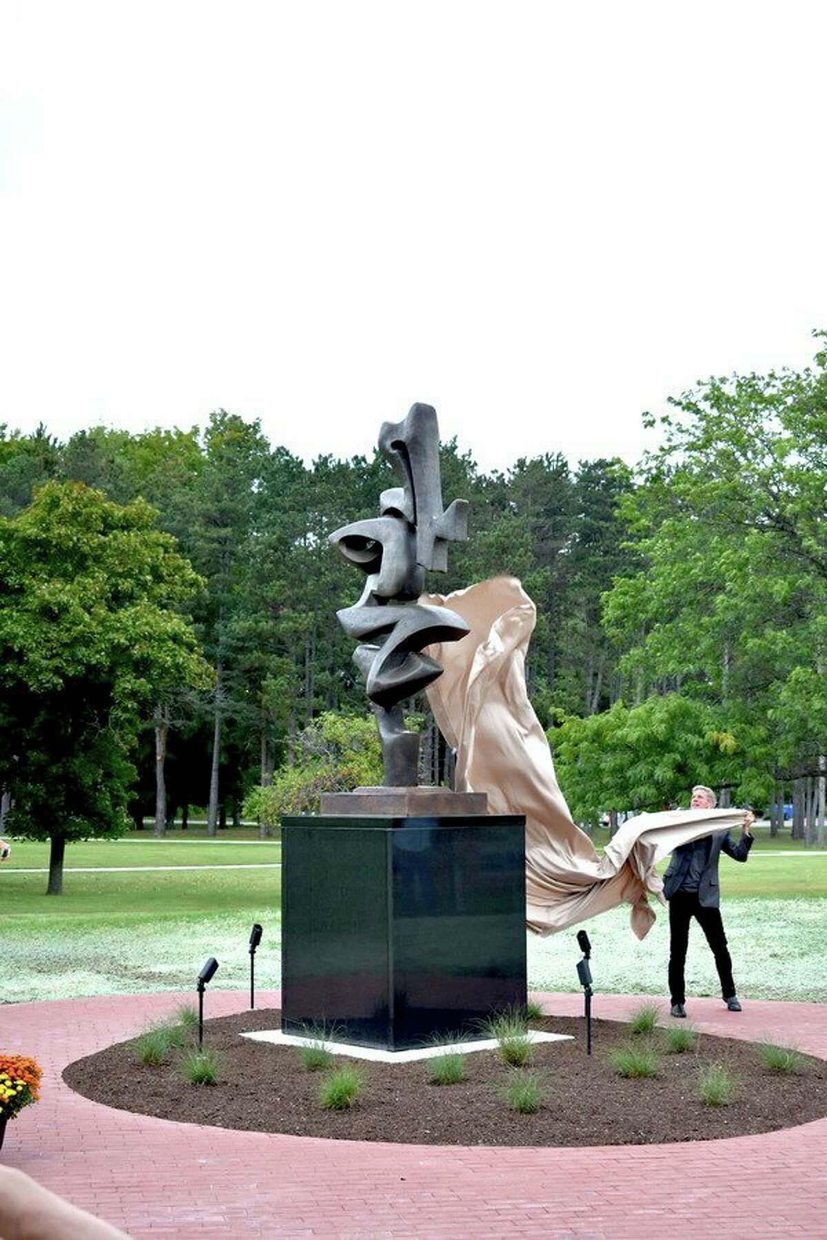 Sculptor sponsor Dr. Andrew Riemer unveils a bronze sculpture at the West Shore Community College Alumni Plaza, the first large-scale sculpture by Riverton Township artist Manierre Dawson. (Courtesy Photo)