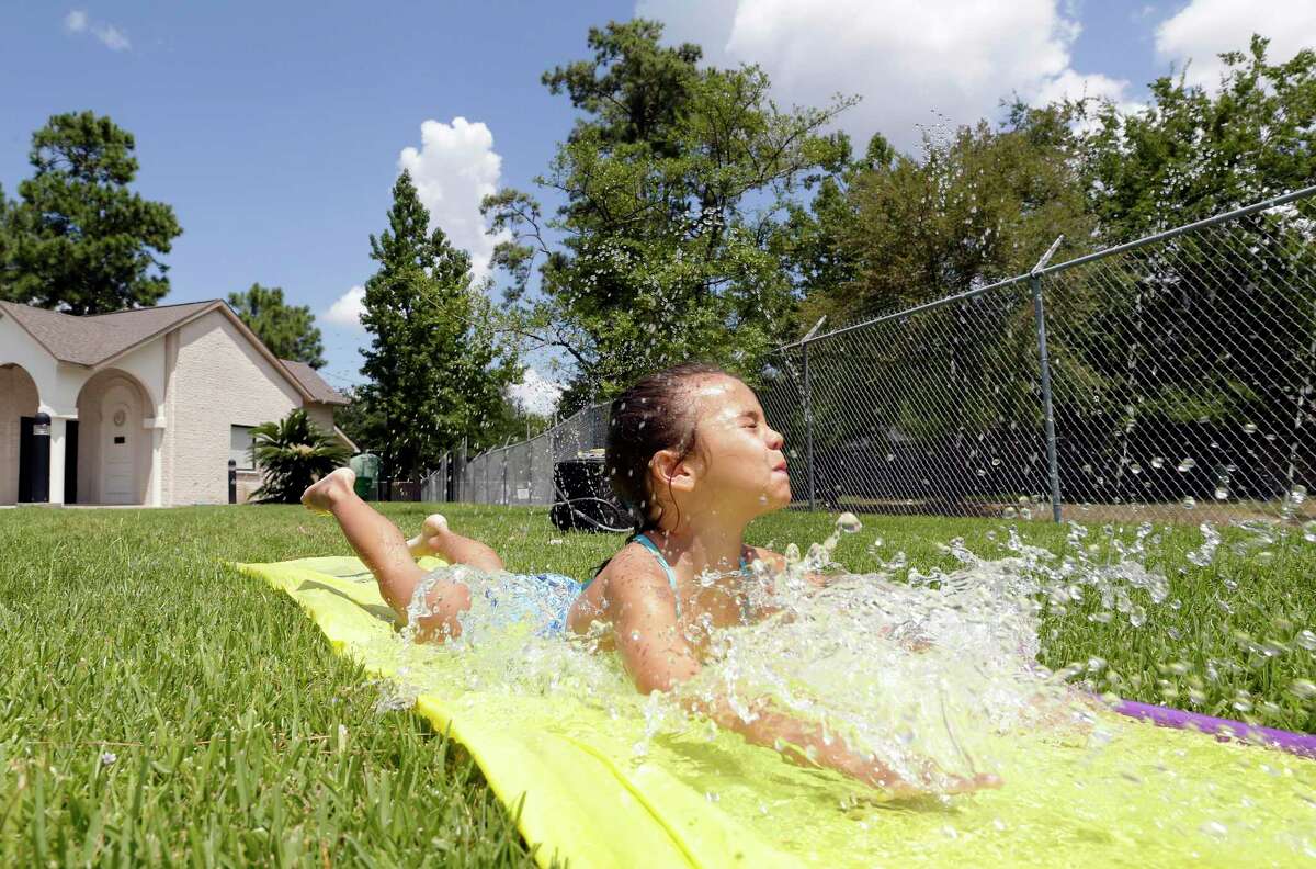 Aubrey Collins, age five, plays on a Slip-N-Slide during a "Meet the Fireman" neighborhood gathering for Wimbledon Champions residents Saturday, Aug. 17, 2019 at the neighborhood clubhouse in Spring, TX.